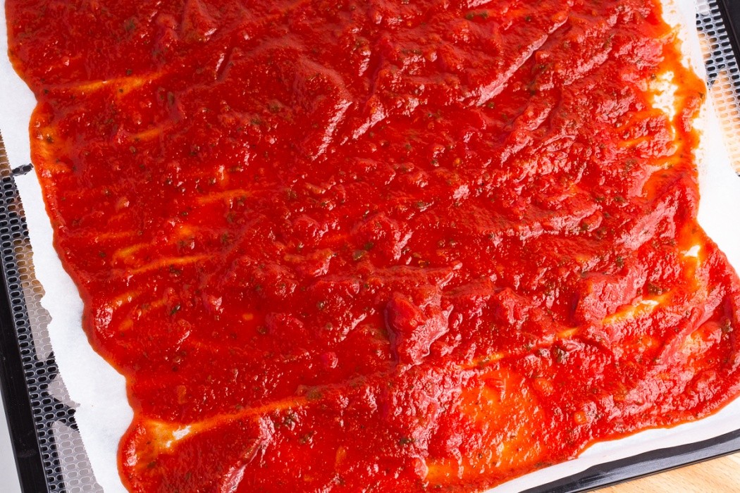 Spread as evenly and thinly as possible and flip half way through drying pasta sauce spread on parchment paper before dehydrating
