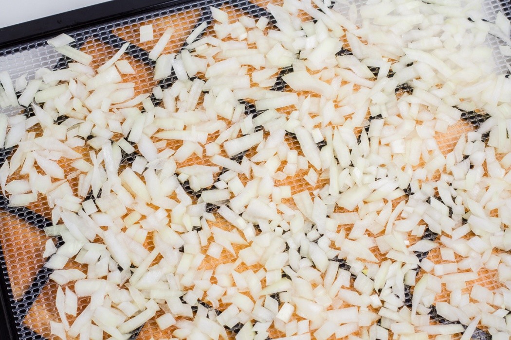Spread the onions evenly on a dehydrator tray, they can touch and overlap but avoid stacking diced onions spread on a dehydrator tray