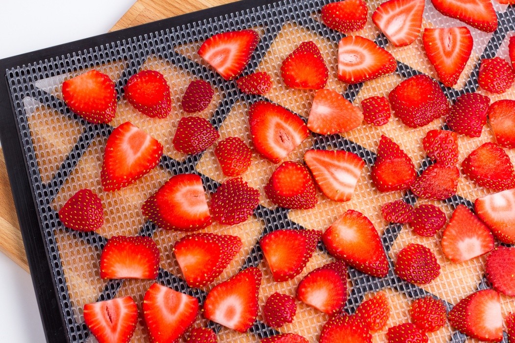 Slice strawberries as thin and possible and spread evenly on dehydrator tray sliced strawberries on a dehydrator tray
