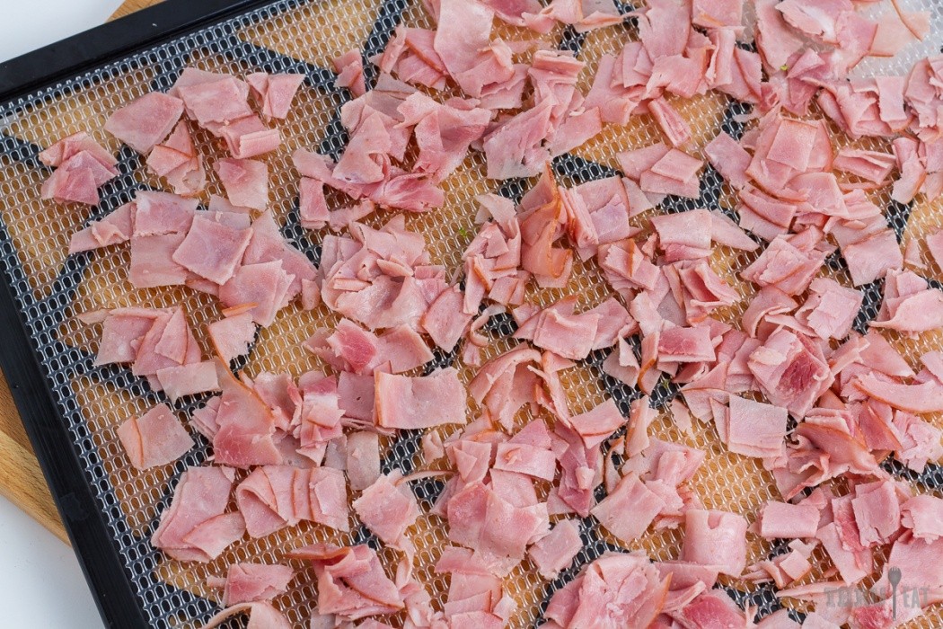 sliced and chopped deli ham on a dehydrator tray