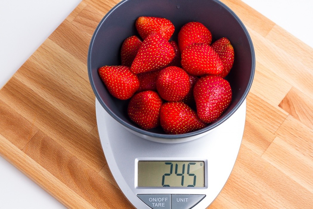 245 grams of strawberries in a blue bowl on a scale