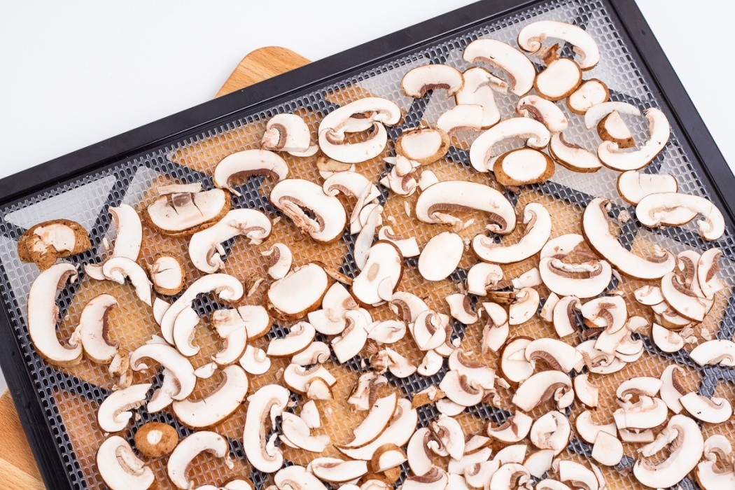sliced baby bella mushrooms on a dehydrator tray