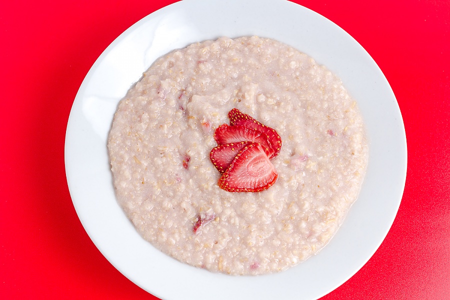Dehydrated strawberries rehydrate really well and are a great addition to oatmeal cooked strawberries and cream oatmeal on a red background