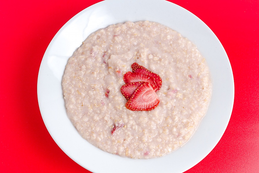 cooked strawberries and cream oatmeal on a red background