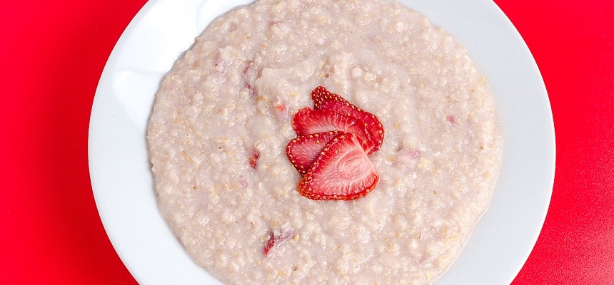 cooked strawberries and cream oatmeal on a red background