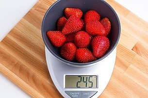 245 grams of strawberries in a blue bowl on a scale