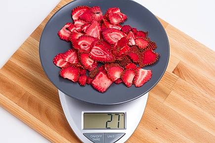 27 grams of dried strawberries on a blue plate on a scale