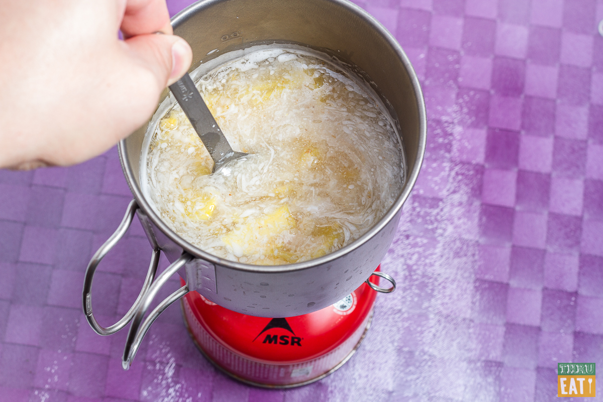 stirring piña colada cream of wheat in a backpacking stove